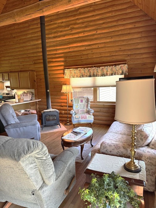 living area with a wood stove, log walls, high vaulted ceiling, and hardwood / wood-style floors