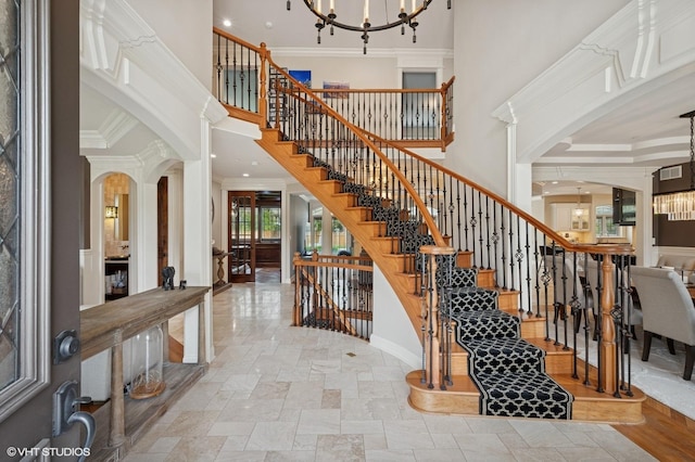 3244 Lakeside Ave, Northbrook, IL 60062 - staircase featuring a towering ceiling, crown molding, arched walkways, stone tile flooring, and a notable chandelier