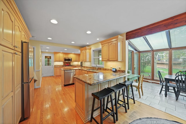 227 Abbott Pl, Tower Lakes, IL 60010 - kitchen with appliances with stainless steel finishes, a peninsula, a breakfast bar area, a sink, and light wood finished floors