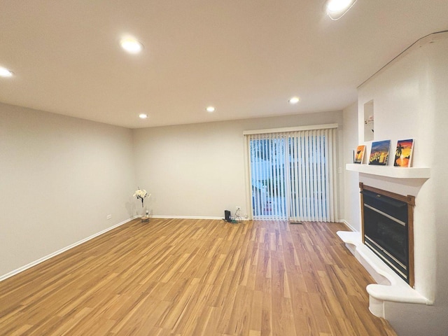 1572 Brandywyn Ln, Buffalo Grove, IL 60089 - unfurnished living room with a glass covered fireplace, recessed lighting, baseboards, and light wood-type flooring