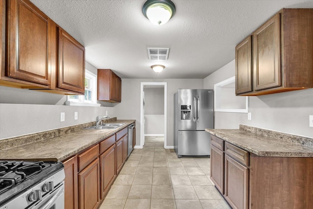 902 N Lincoln Ave, Urbana, IL 61801 - kitchen with appliances with stainless steel finishes, a sink, light tile patterned floors, brown cabinets, and a textured ceiling