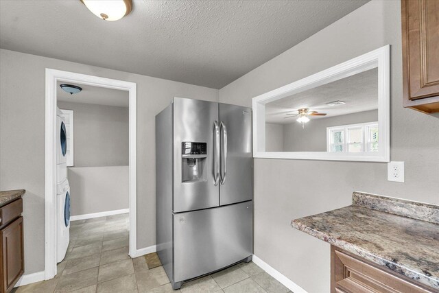 902 N Lincoln Ave, Urbana, IL 61801 - kitchen featuring stainless steel fridge with ice dispenser, stacked washer / dryer, ceiling fan, a textured ceiling, and brown cabinets