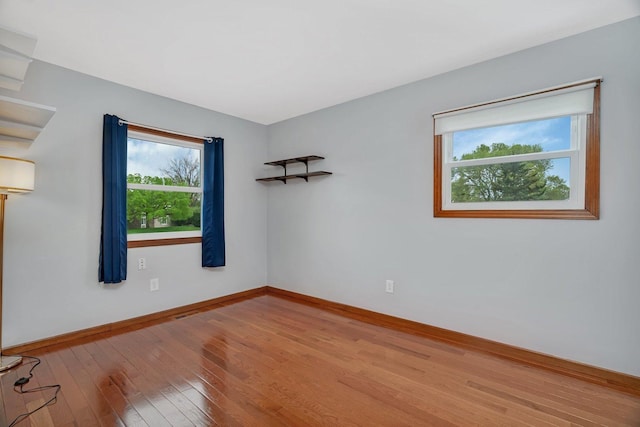 spare room with baseboards and wood finished floors