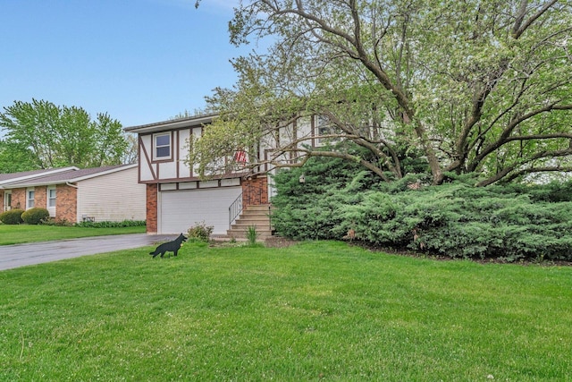 view of front of property with brick siding, an attached garage, a front lawn, and aphalt driveway