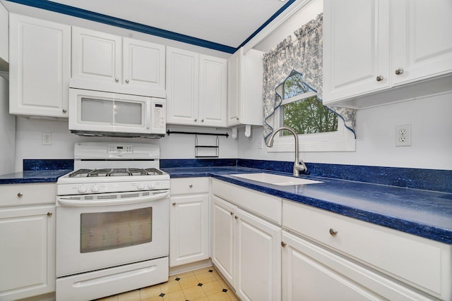 kitchen with a sink, dark countertops, white cabinets, and white appliances