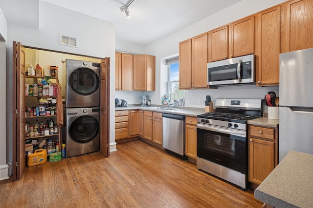 kitchen featuring visible vents, stacked washer and clothes dryer, light wood-style floors, light countertops, and appliances with stainless steel finishes