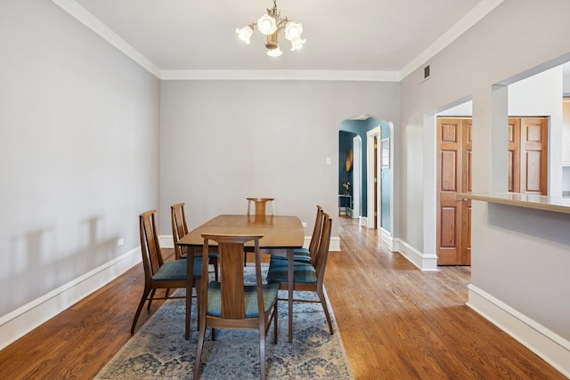 dining space with an inviting chandelier, visible vents, ornamental molding, light wood-style floors, and arched walkways