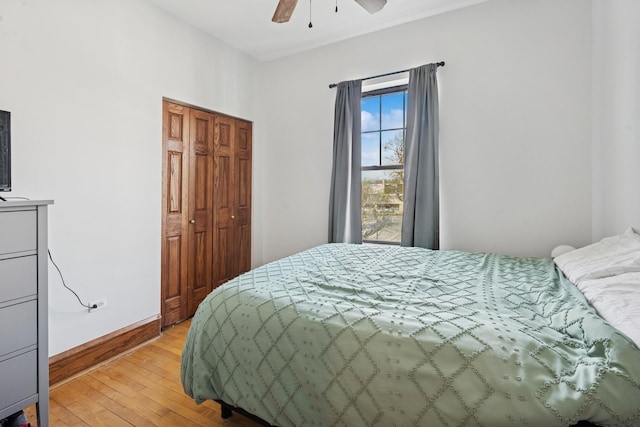 bedroom with light wood-style floors, baseboards, ceiling fan, and a closet