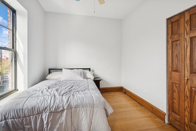 bedroom featuring light wood-style floors, baseboards, multiple windows, and ceiling fan