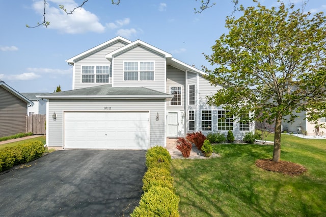 traditional home with a garage, fence, driveway, and a front lawn