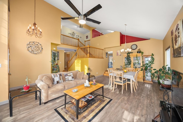 living room featuring stairway, high vaulted ceiling, baseboards, and wood finished floors