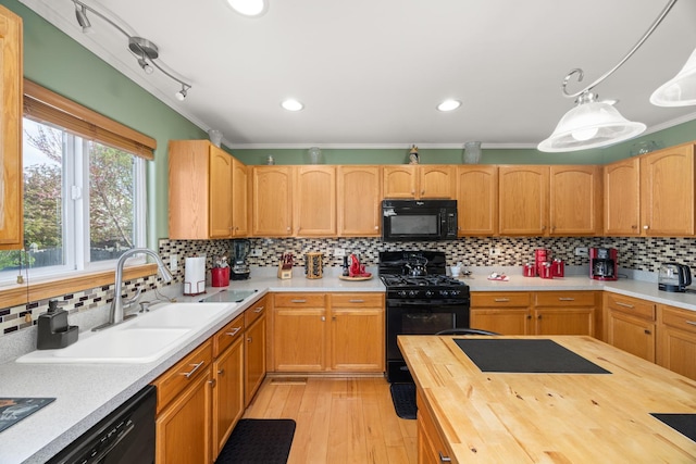 kitchen with decorative backsplash, a sink, black appliances, butcher block counters, and light wood-style flooring