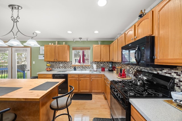 kitchen featuring butcher block countertops, a breakfast bar area, light wood-type flooring, a sink, and black appliances