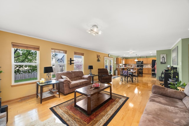living room with baseboards, ornamental molding, and light wood-style flooring