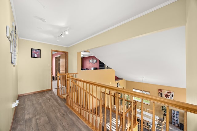 hall with crown molding, wood finished floors, baseboards, rail lighting, and an upstairs landing