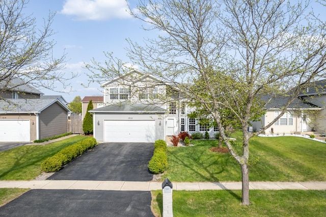 traditional home with a garage, a front lawn, and aphalt driveway