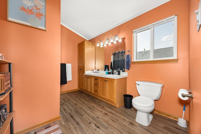 bathroom featuring double vanity, ornamental molding, wood finished floors, and toilet