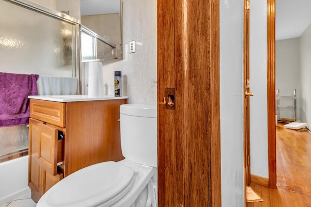 bathroom with vanity, a shower with shower door, toilet, and wood finished floors