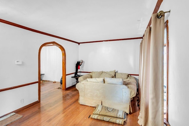 living area featuring crown molding, baseboards, arched walkways, and wood finished floors