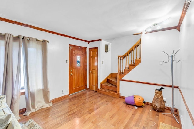 entryway with light wood-style floors, stairs, crown molding, and baseboards