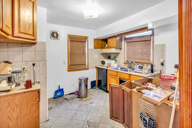 kitchen with black dishwasher, backsplash, a sink, and light countertops