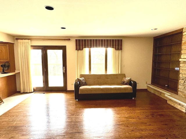 living room featuring plenty of natural light, built in features, and wood finished floors