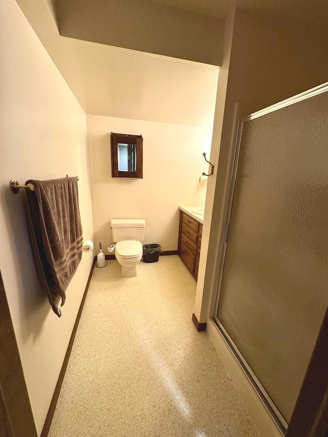 bathroom featuring toilet, baseboards, a shower stall, and vanity