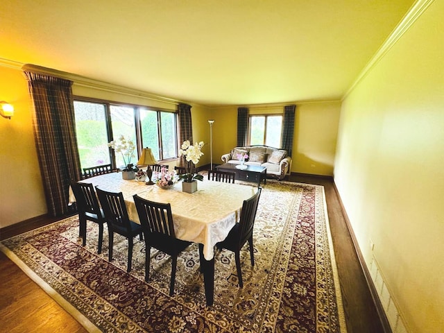 dining space featuring crown molding, baseboards, and wood finished floors