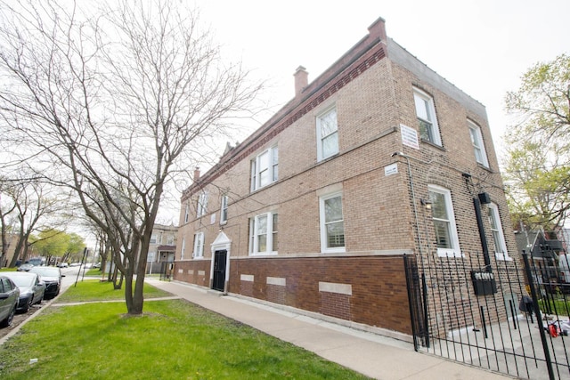 view of property exterior with fence, a chimney, a yard, and brick siding