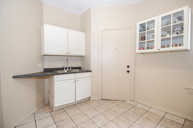 washroom with a sink, baseboards, and light tile patterned flooring