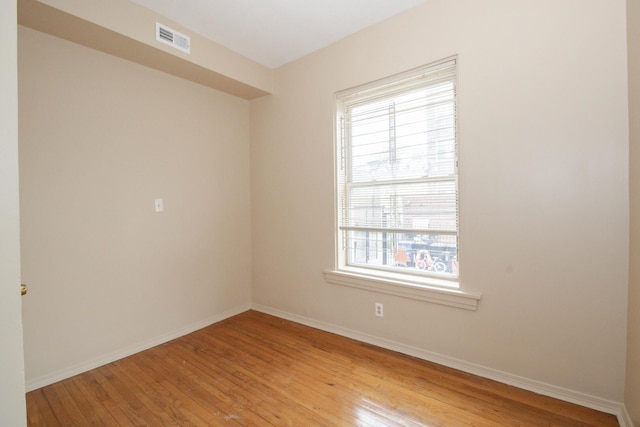 empty room featuring baseboards, visible vents, and light wood finished floors