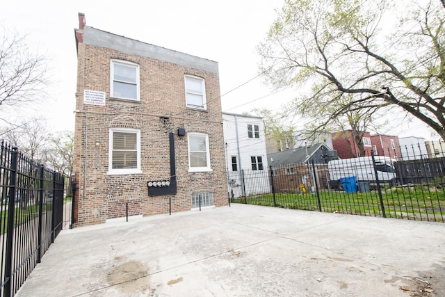 rear view of house featuring fence and brick siding