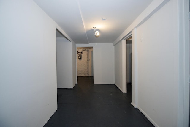 corridor with baseboards and concrete flooring