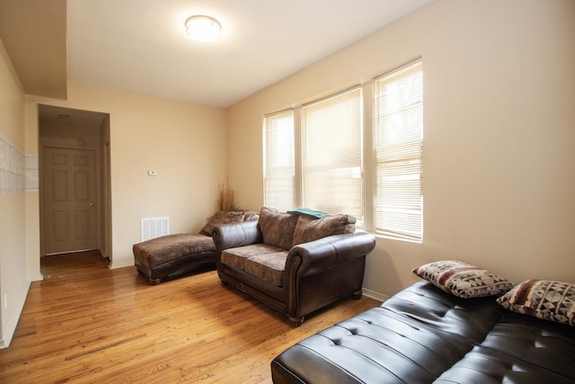 living room with visible vents, light wood-style flooring, and baseboards