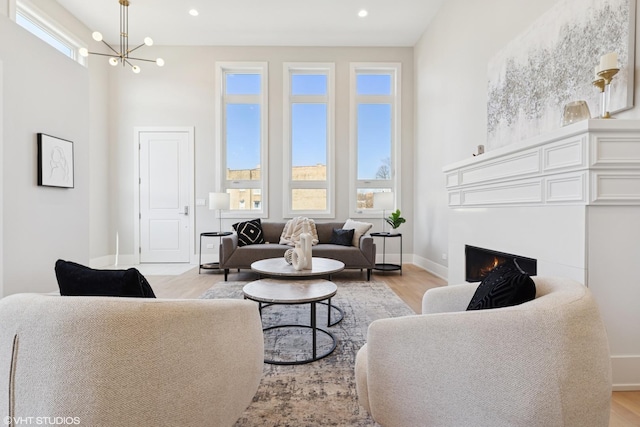 living area with baseboards, a lit fireplace, a wealth of natural light, and light wood-style flooring