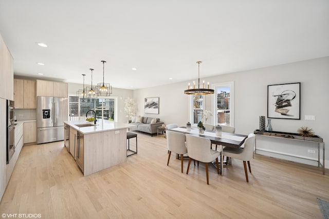 kitchen featuring an inviting chandelier, light brown cabinets, light wood-style floors, modern cabinets, and stainless steel refrigerator with ice dispenser