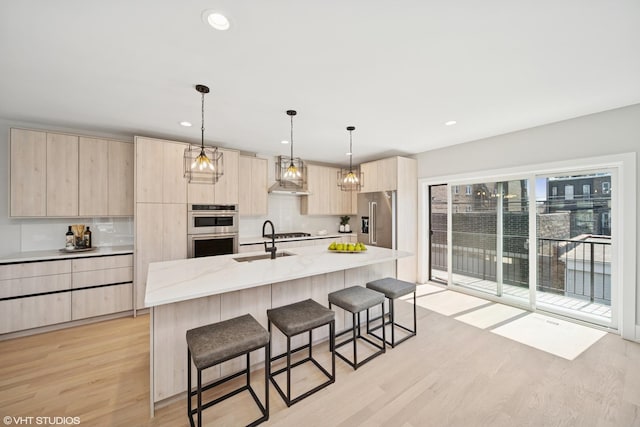 kitchen featuring appliances with stainless steel finishes, light brown cabinets, a kitchen breakfast bar, light wood-type flooring, and modern cabinets