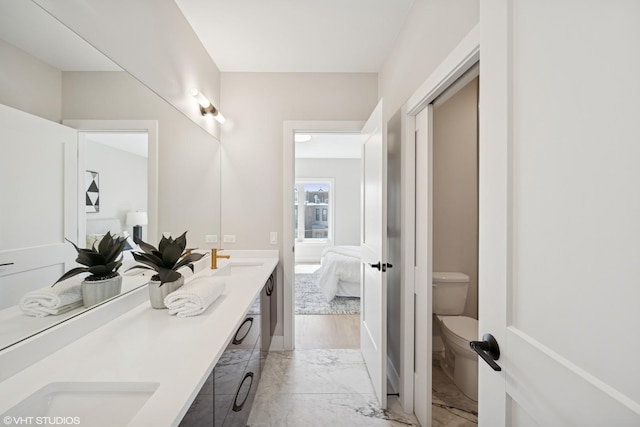full bathroom with double vanity, marble finish floor, toilet, connected bathroom, and a sink