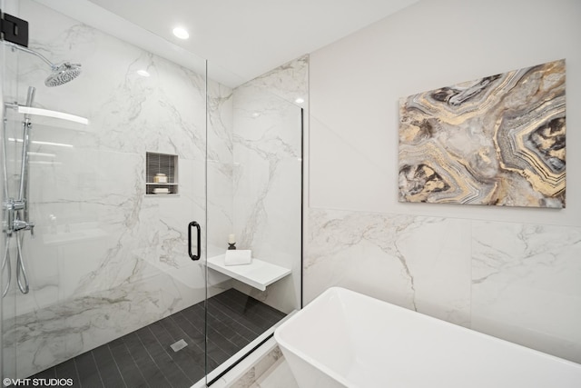 full bathroom with a freestanding tub, tile walls, recessed lighting, and a marble finish shower