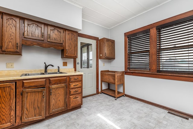 115 Van Buren St, Savanna, IL 61074 - kitchen featuring a sink, light flooring, ornamental molding, light countertops, and brown cabinetry