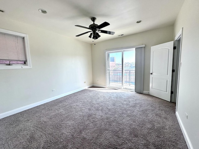 carpeted spare room with baseboards, visible vents, and ceiling fan