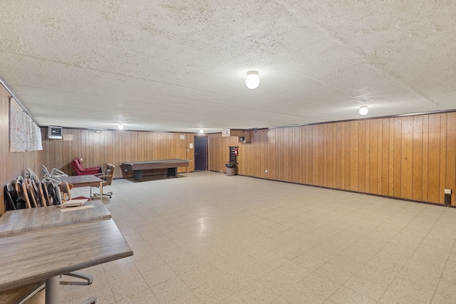 finished below grade area with a textured ceiling, wooden walls, tile patterned floors, and billiards