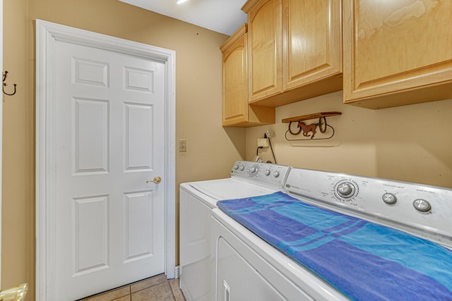 clothes washing area featuring light tile patterned floors, washing machine and dryer, and cabinet space