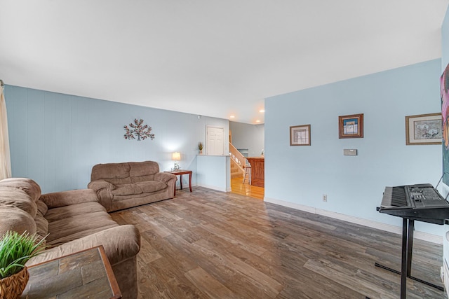 living area featuring baseboards, wood finished floors, and stairway