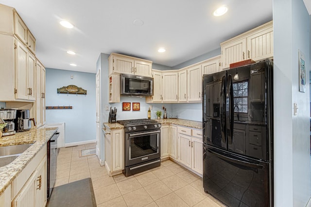 kitchen with light stone countertops, baseboards, light tile patterned floors, cream cabinetry, and black appliances