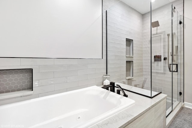 full bathroom featuring a stall shower and a tub with jets
