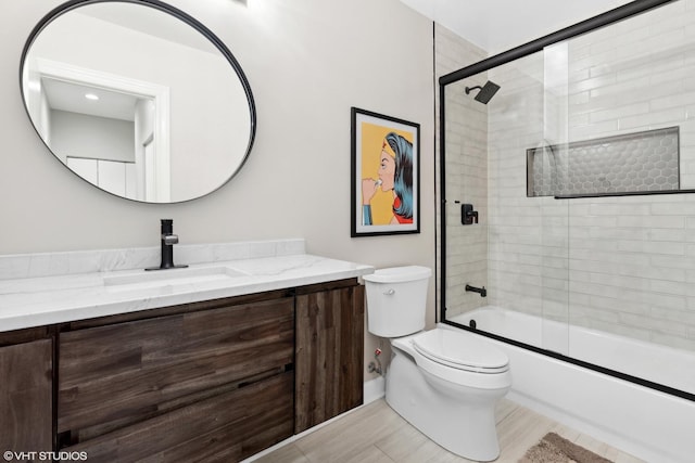 full bathroom featuring toilet, shower / bath combination with glass door, and vanity