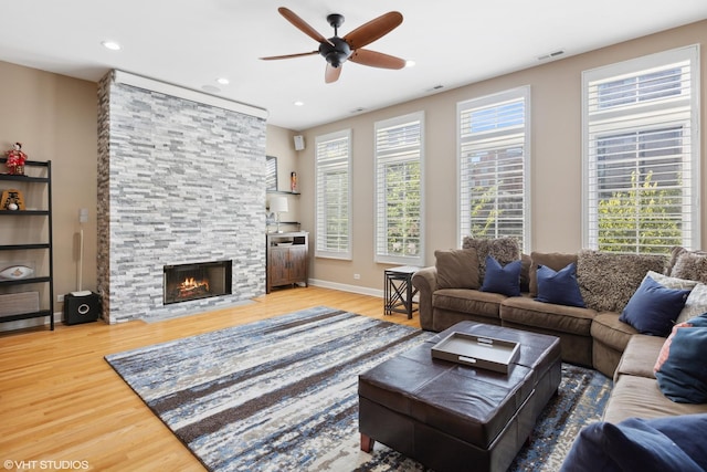 living room featuring visible vents, wood finished floors, a stone fireplace, recessed lighting, and a ceiling fan