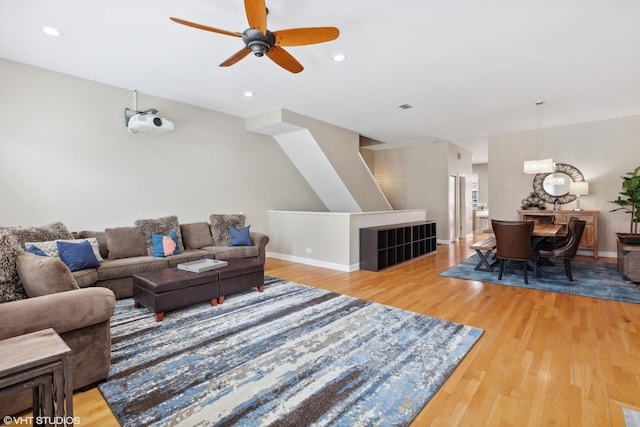 living area featuring light wood-type flooring, recessed lighting, baseboards, and ceiling fan with notable chandelier