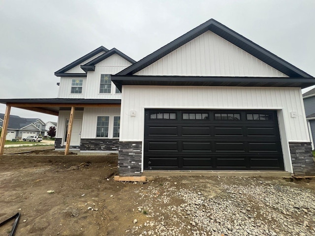 302 Sutton Dr, Savoy, IL 61874 - modern farmhouse with stone siding, an attached garage, a porch, and driveway